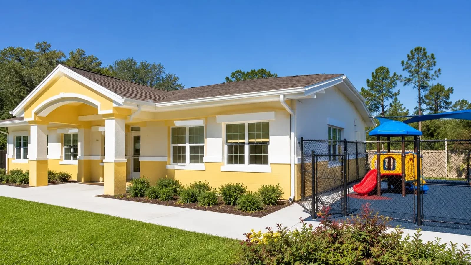 A cheerful daycare center building exterior with a fenced outdoor play area